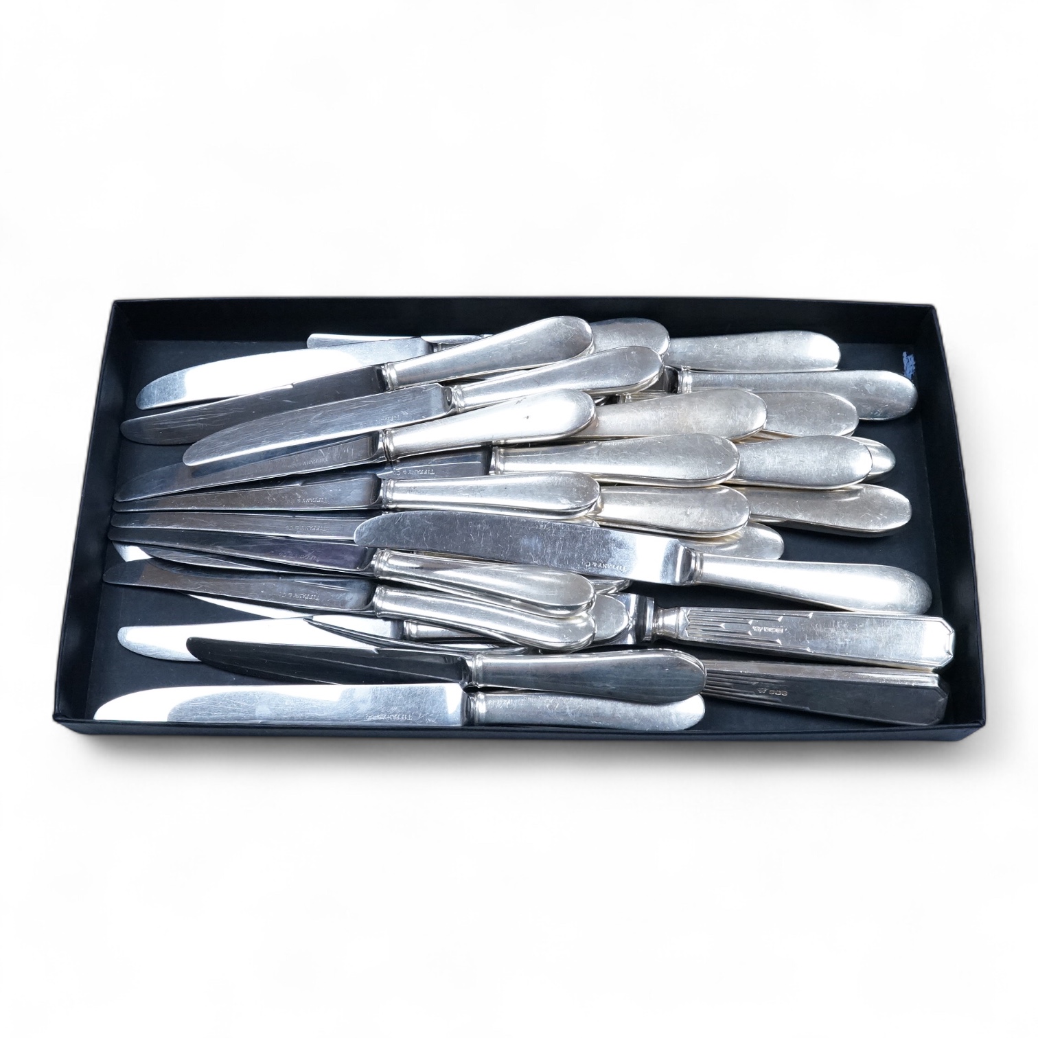 A set of twelve white metal handled steel table knives and thirteen matching dessert knives(one a.f.), all blades bearing the etched inscription 'Tiffany & Co', table knife 24.1cm, together with a silver handled carving